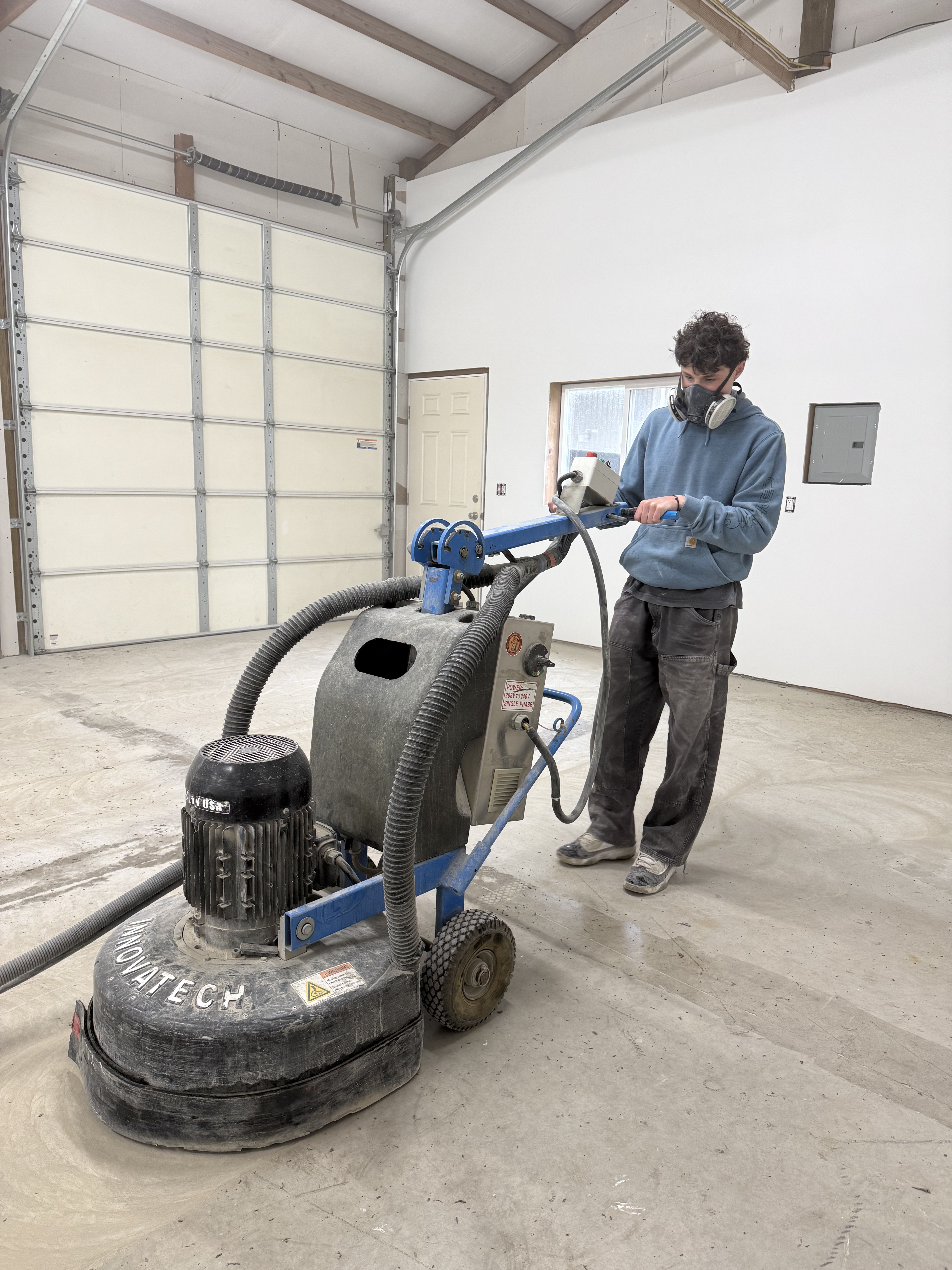 Reegan, owner of Precision Epoxy Flooring, preparing a garage floor